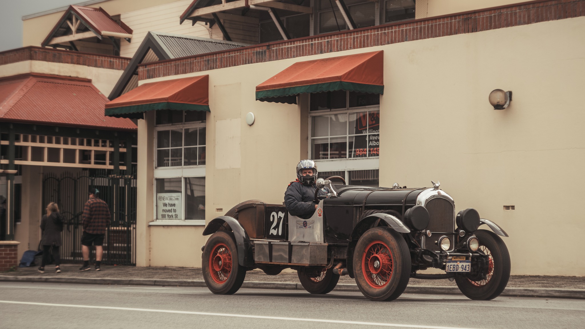 A vintage car going down a road