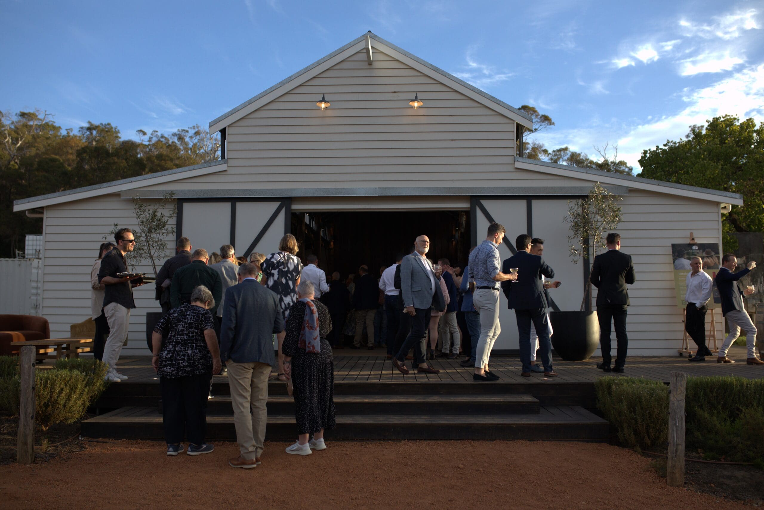 Group of people standing infront of a barn-like building