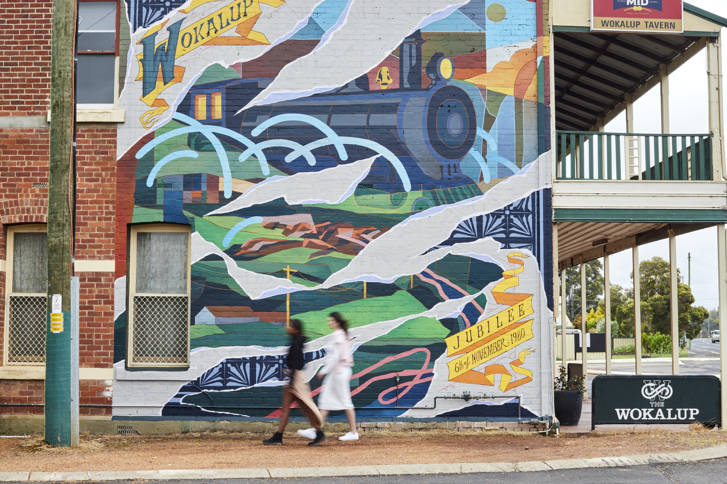 People walk beside the vibrant street art in the centre of Harvey Region.