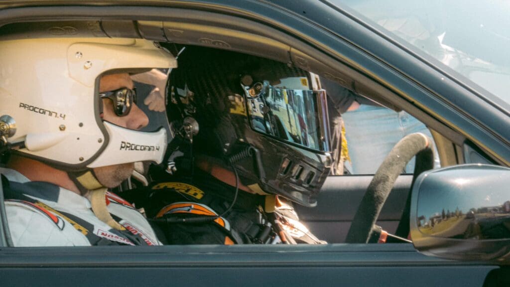 Two people sitting in a racecar with helmets on