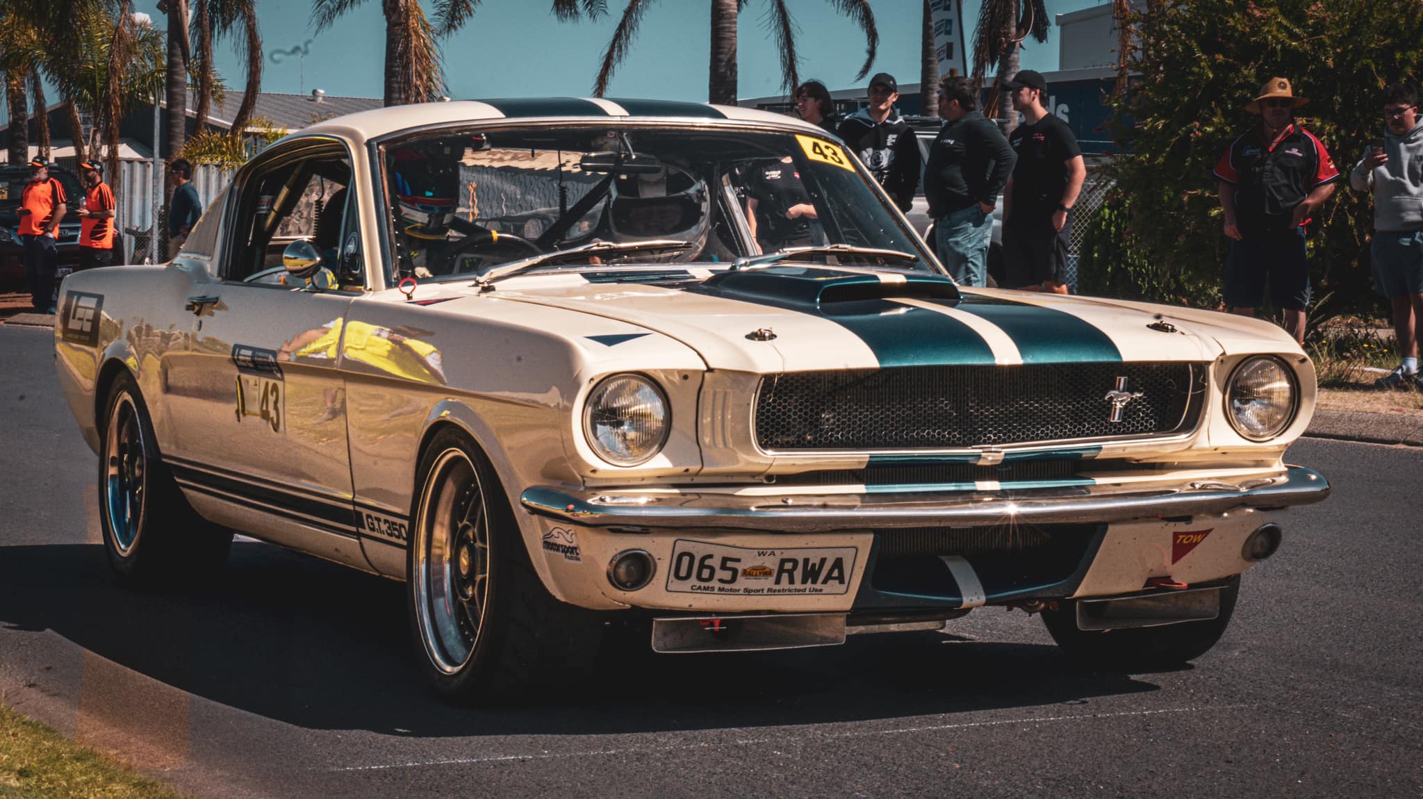A white vintage racing car with blue stripes